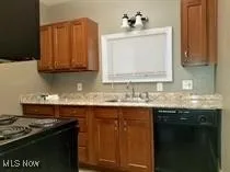 Kitchen with dishwasher, brown cabinetry, light countertops, and range with electric cooktop