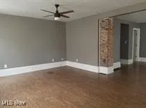 Unfurnished room with ceiling fan and dark wood finished floors
