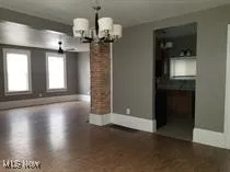 Unfurnished dining area featuring a chandelier and baseboards