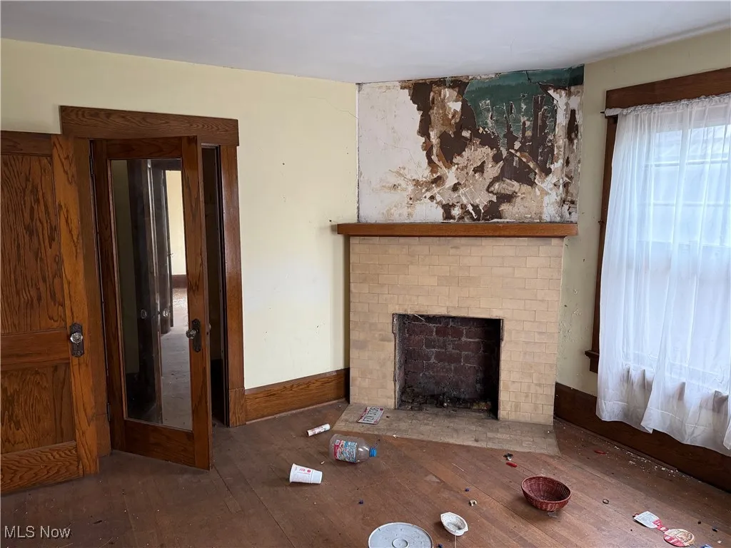 Unfurnished living room featuring a brick fireplace and hardwood / wood-style flooring