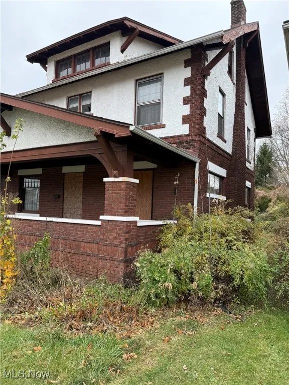 View of front facade with brick siding, stucco siding, and a chimney