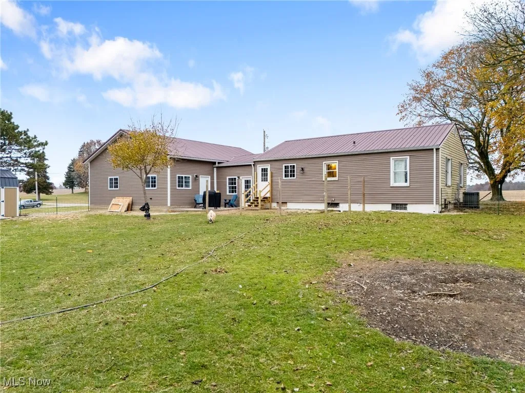 Rear view of house featuring a lawn, a metal roof, and entry steps