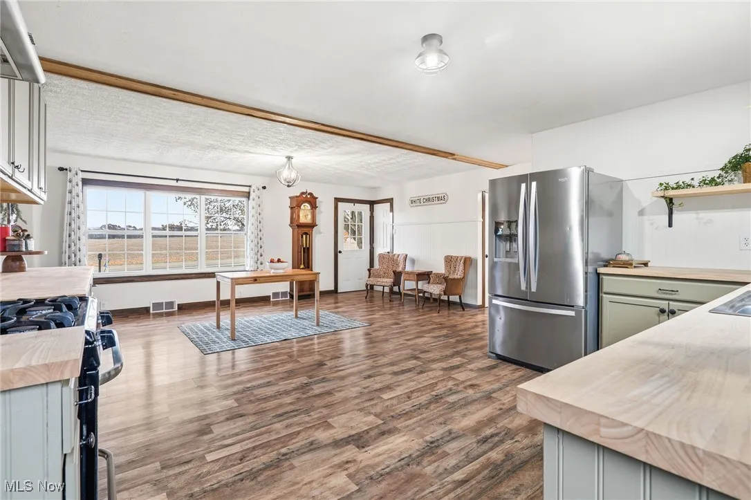 Kitchen with wooden counters, stainless steel refrigerator with ice dispenser, and dark wood-style flooring