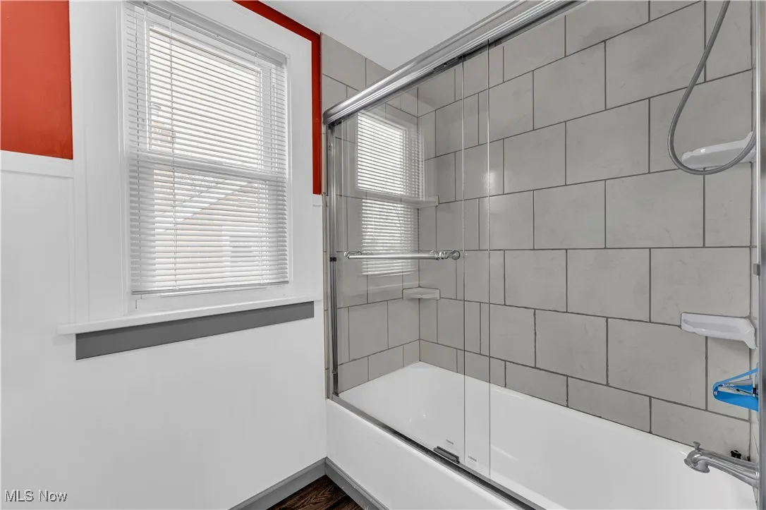 Full bath featuring shower / bath combination with glass door