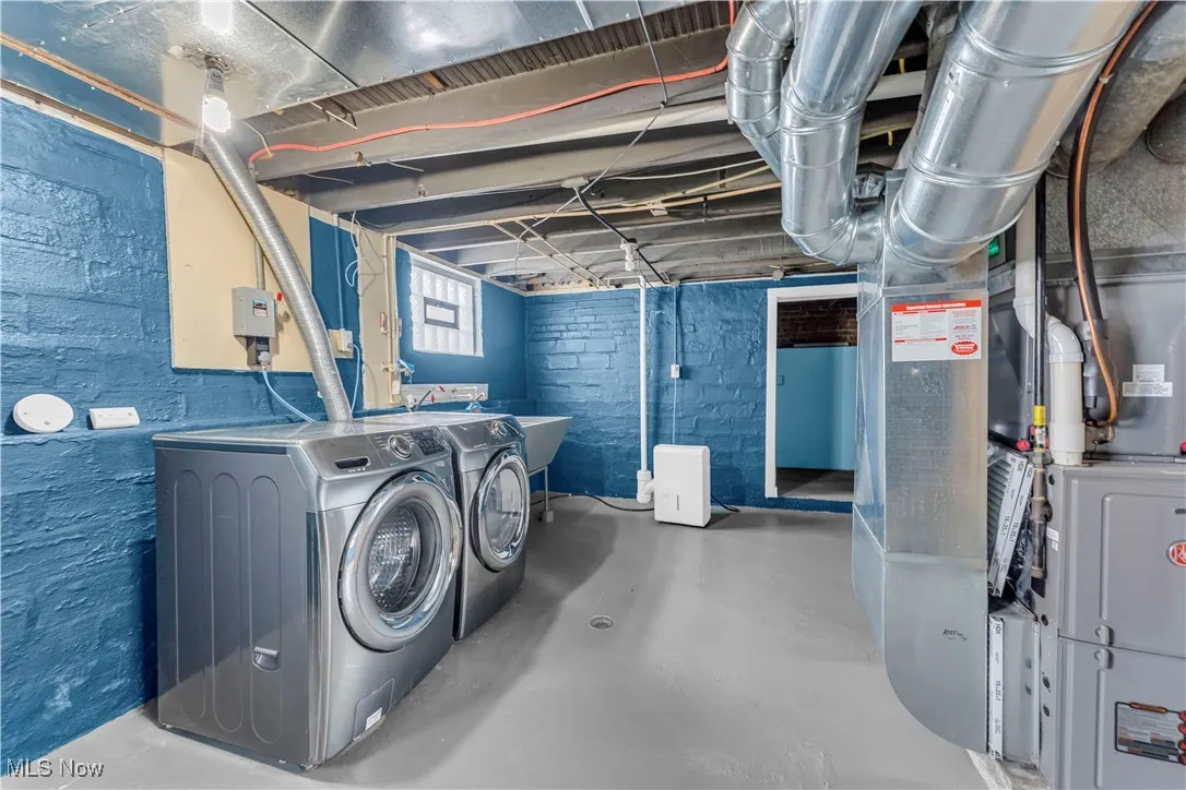 Laundry room with finished concrete floors, heating unit, and washer and clothes dryer