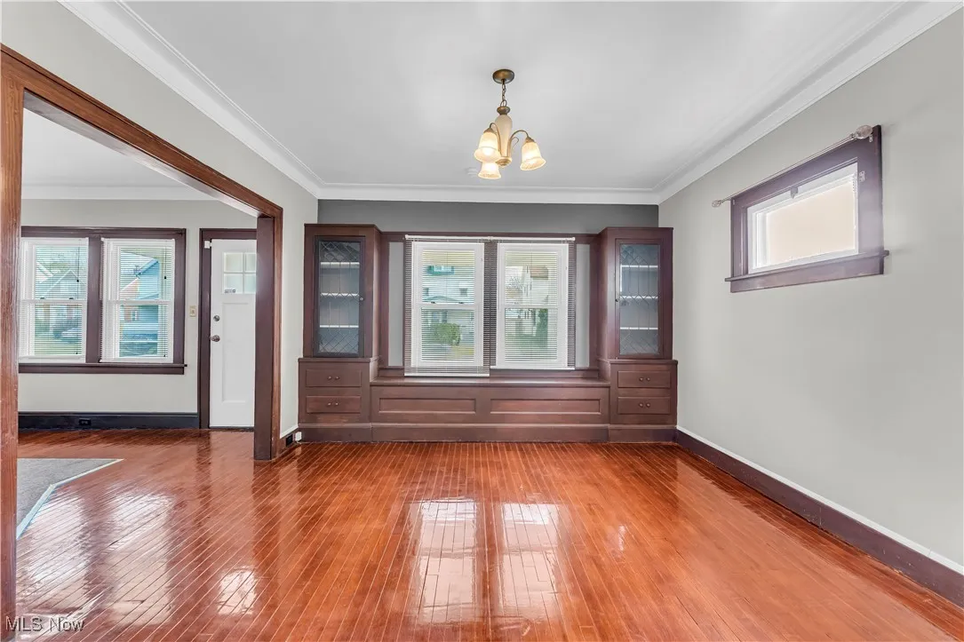 Unfurnished dining area featuring a chandelier, crown molding, and hardwood / wood-style flooring