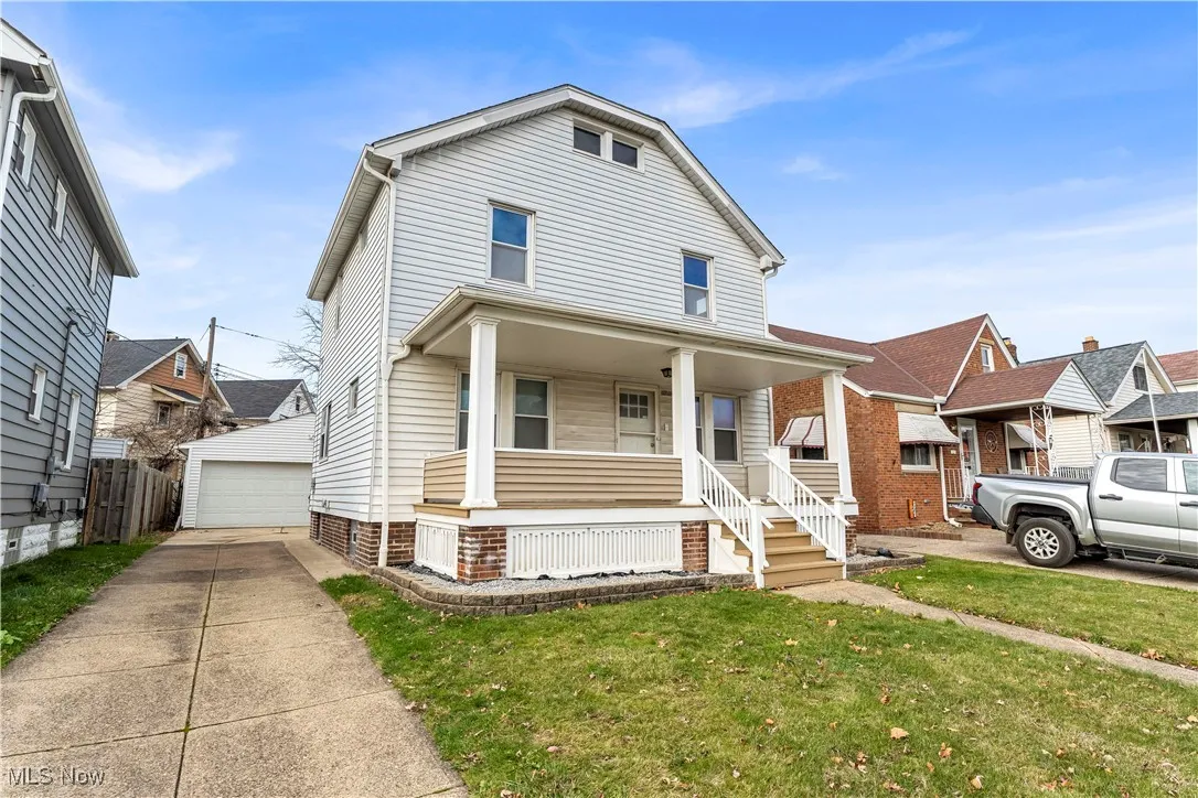 American foursquare style home with covered porch, an outbuilding, and a garage