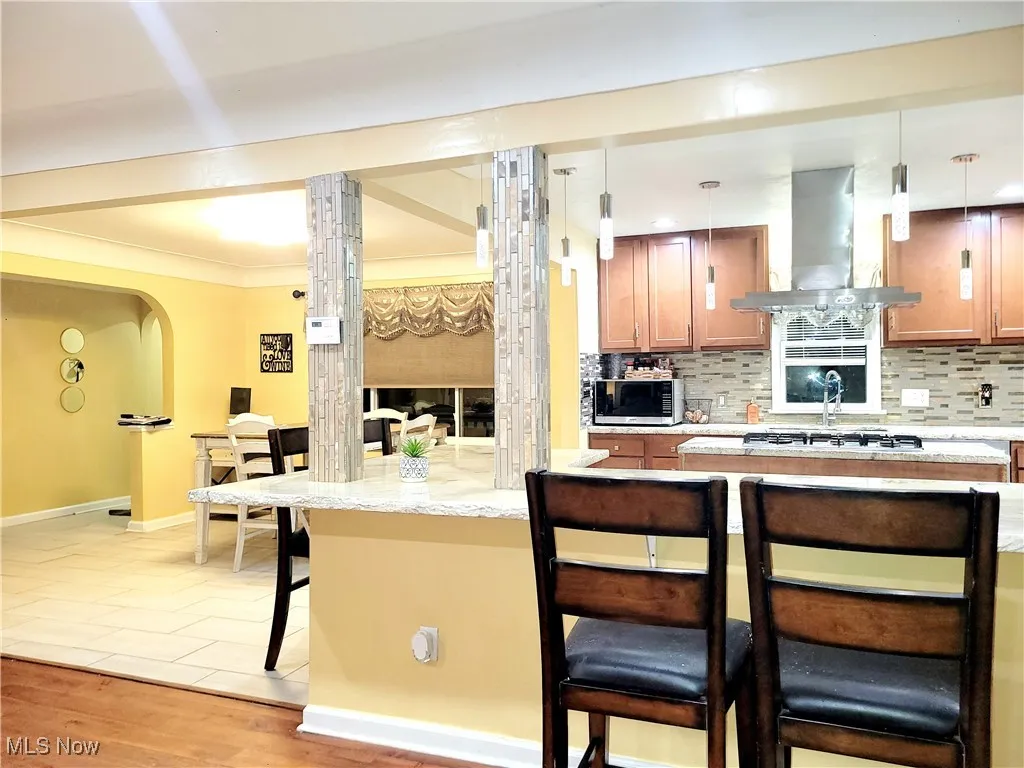Kitchen featuring a breakfast bar, tasteful backsplash, extractor fan and decorative light fixtures