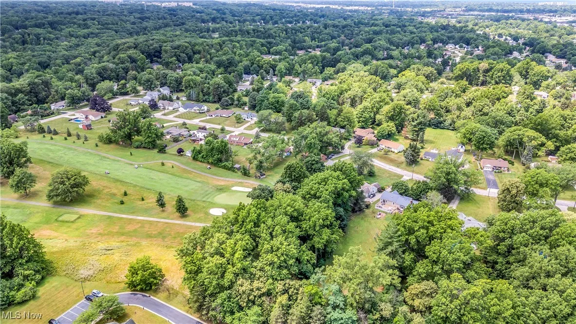 Aerial view of property and surrounding area featuring nearby suburban area and a golf club