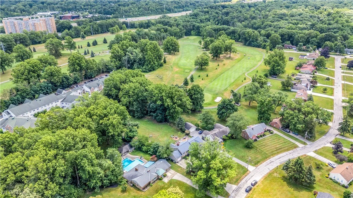 Aerial view of residential area featuring a tree filled landscape and a golf course