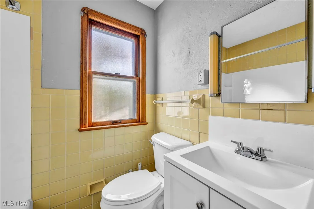 Bathroom with a shower, vanity, tile walls, and a textured wall