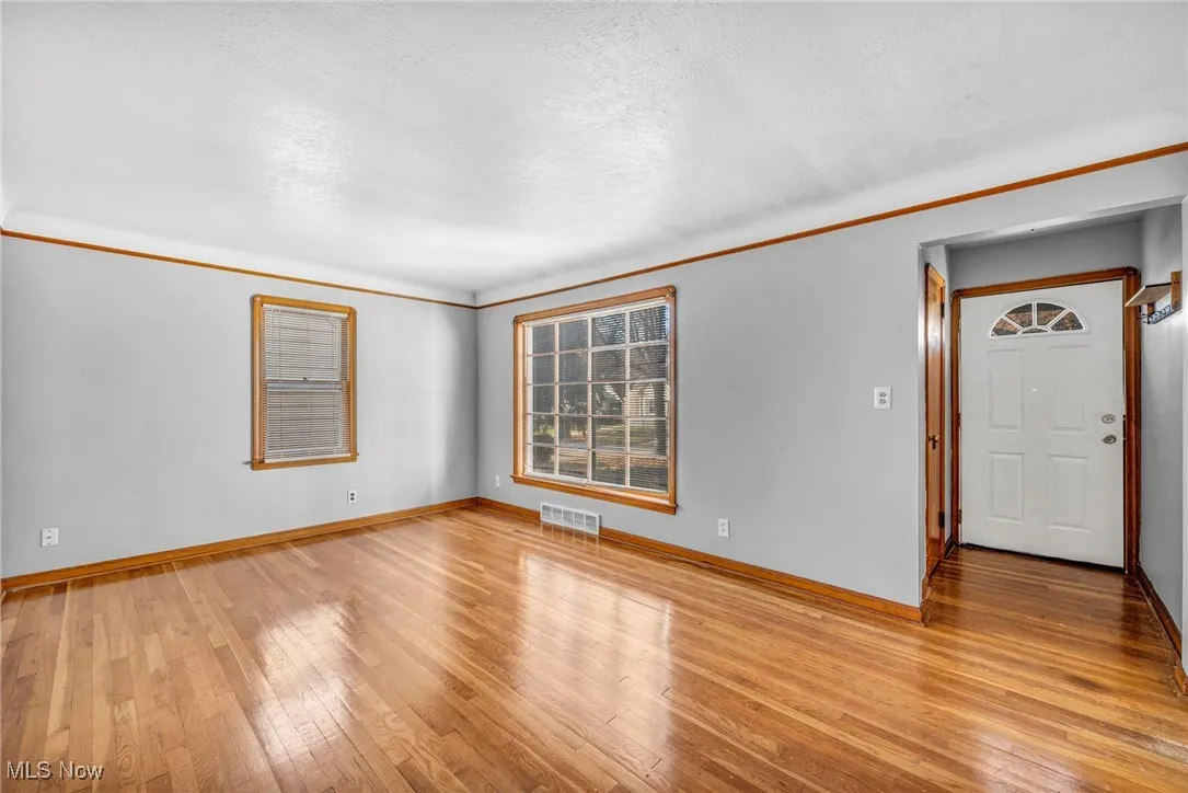Unfurnished room featuring light wood-style flooring, crown molding, and a textured ceiling