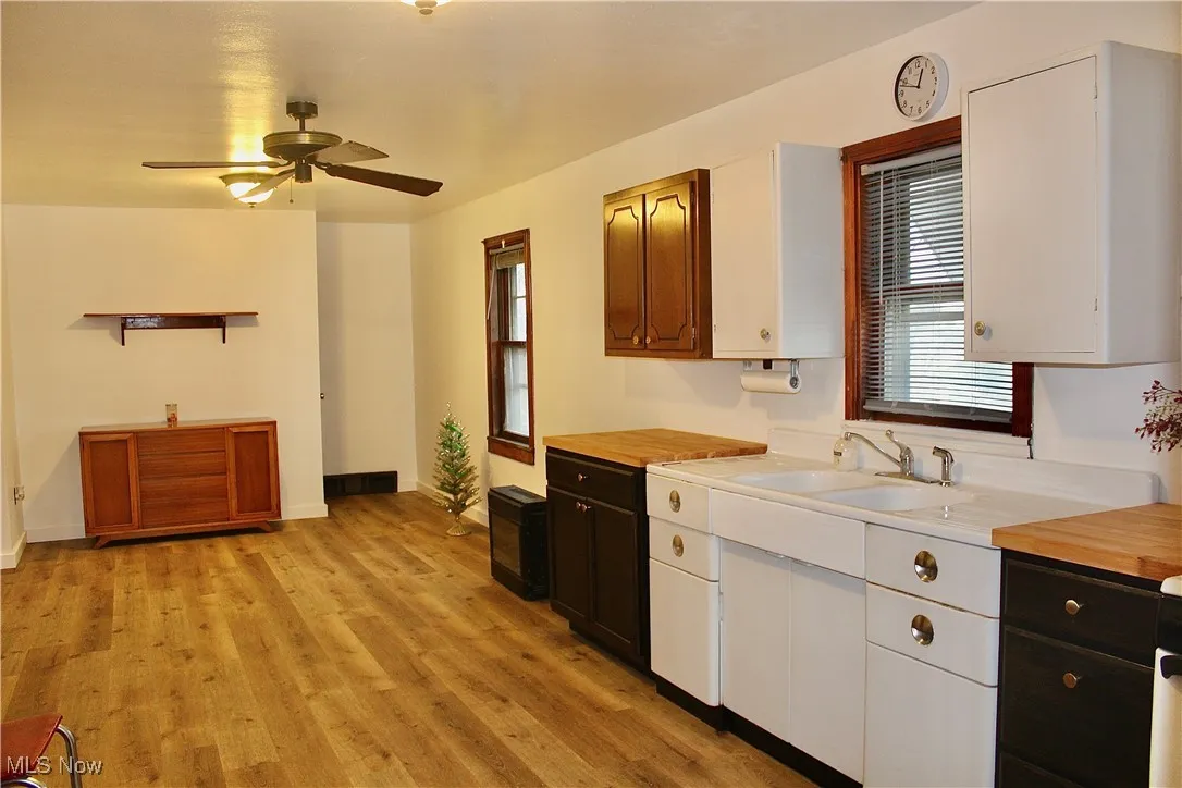 Kitchen with light wood-style flooring, ceiling fan, and white cabinets