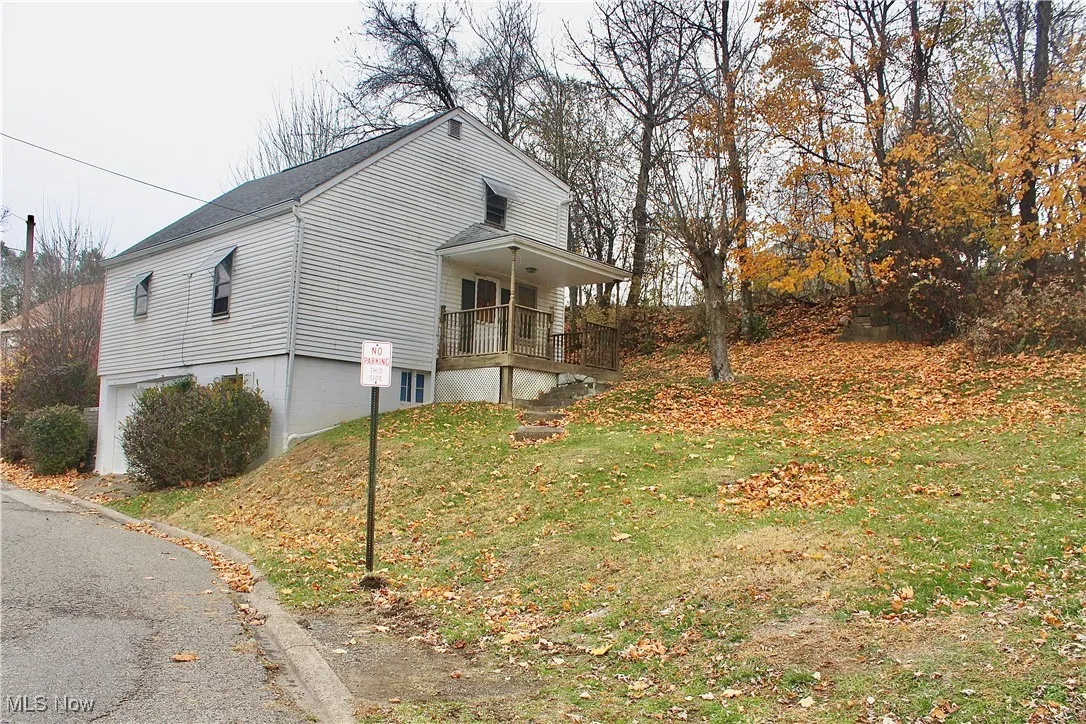 View of home's exterior with a lawn, a porch, and a shingled roof