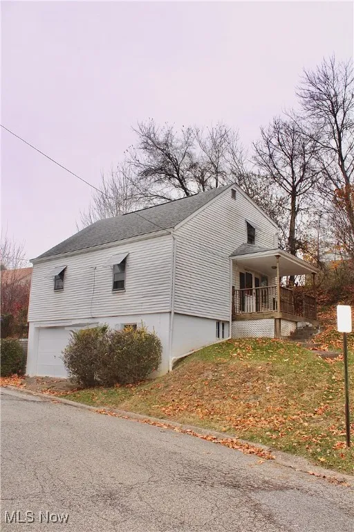View of home's exterior with covered porch, a shingled roof, and an attached garage