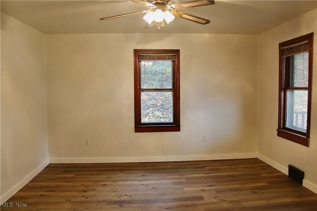 Spare room with dark wood-style floors and a ceiling fan
