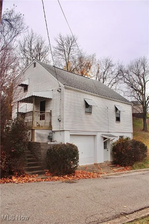 View of home's exterior featuring roof with shingles, stairs, and a garage