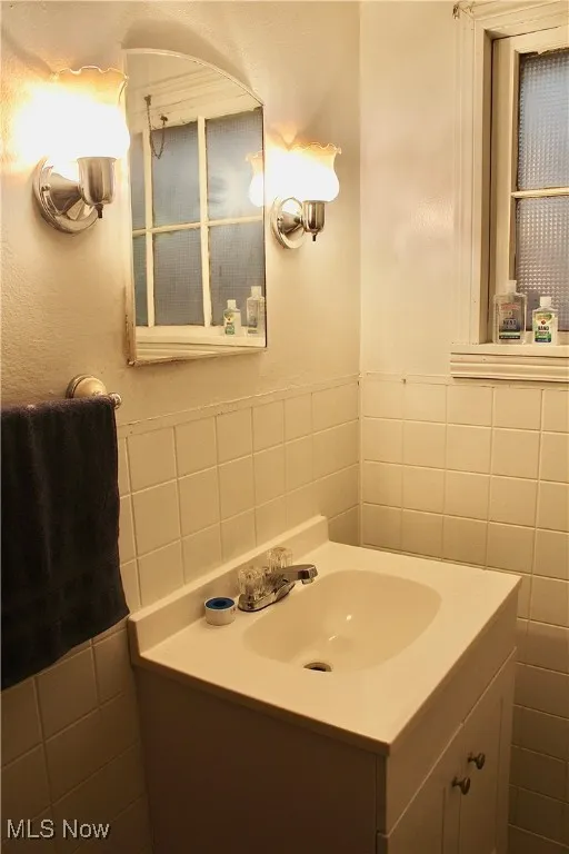 Bathroom featuring tile walls, vanity, and wainscoting