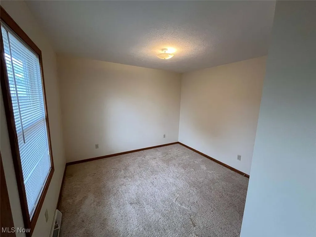 Empty room with a textured ceiling and carpet flooring