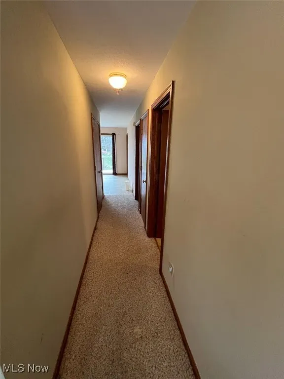 Corridor featuring light carpet and baseboards