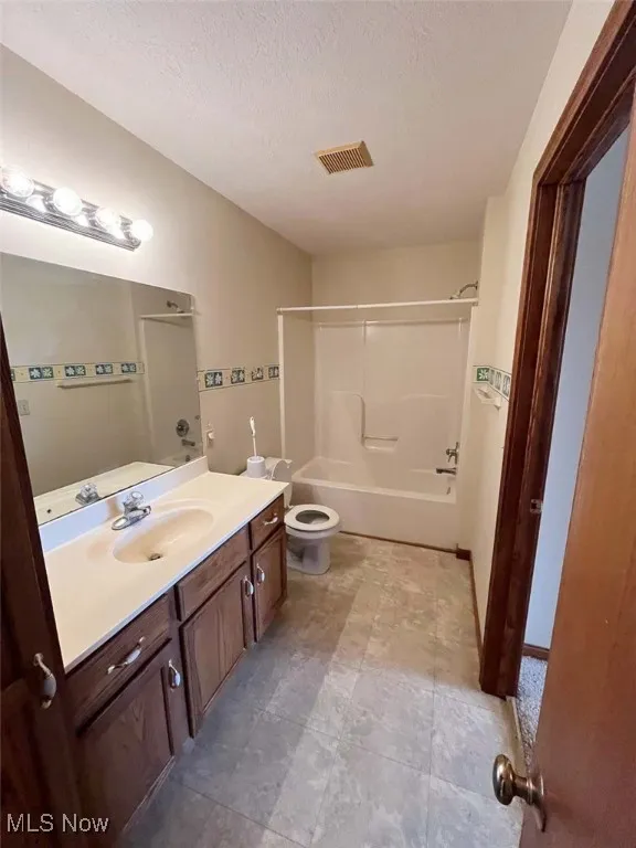 Full bath featuring vanity, bathing tub / shower combination, and a textured ceiling