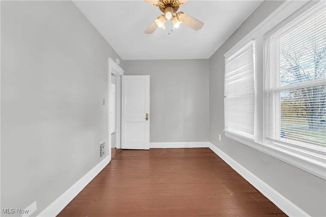 Unfurnished room featuring dark wood finished floors and a ceiling fan
