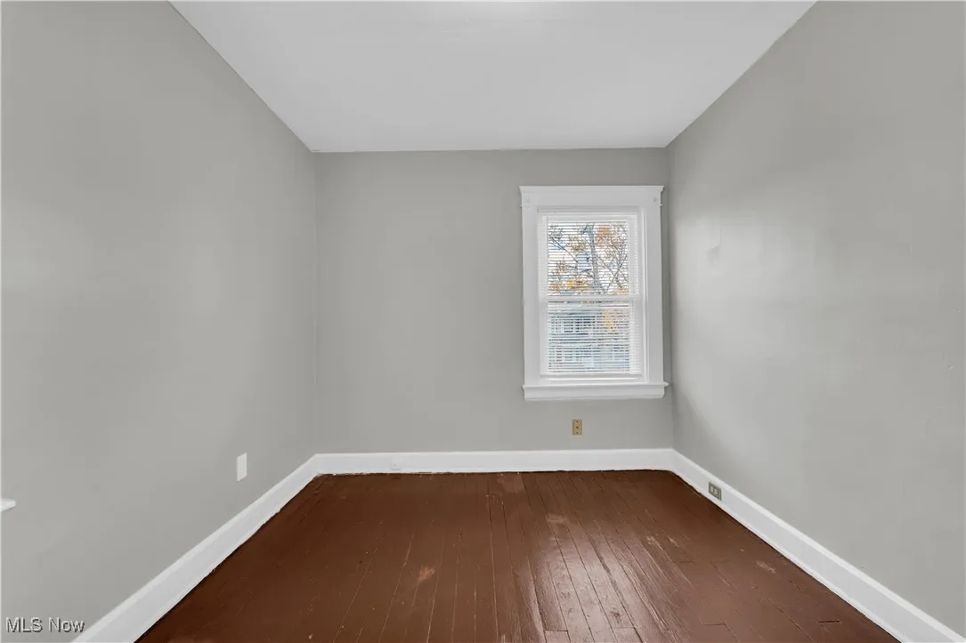 Spare room featuring dark wood-style flooring and baseboards