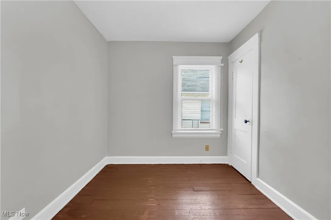 Empty room featuring baseboards and dark wood-style flooring