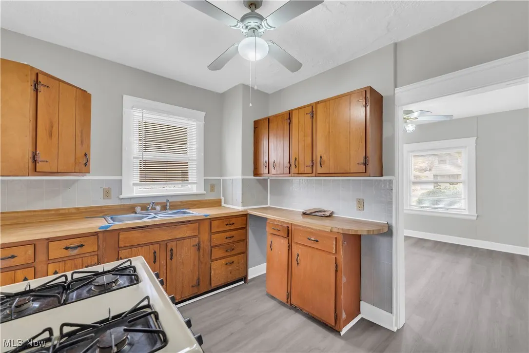 Kitchen featuring brown cabinets, light countertops, light wood-style flooring, a ceiling fan, and decorative backsplash