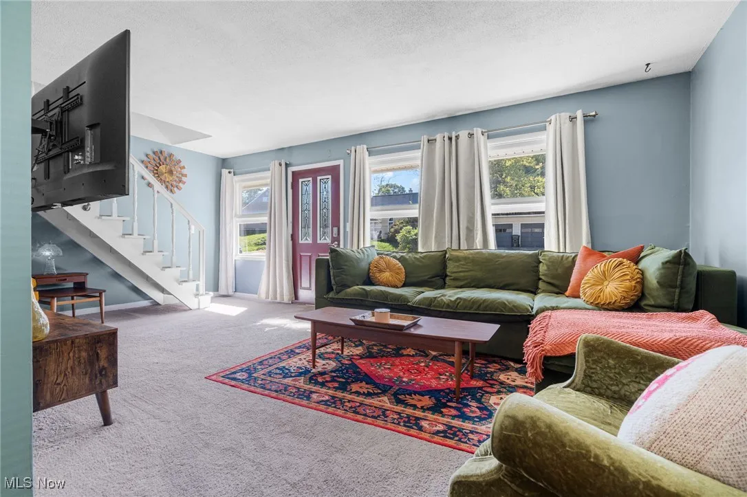 Carpeted living area with a textured ceiling and stairway