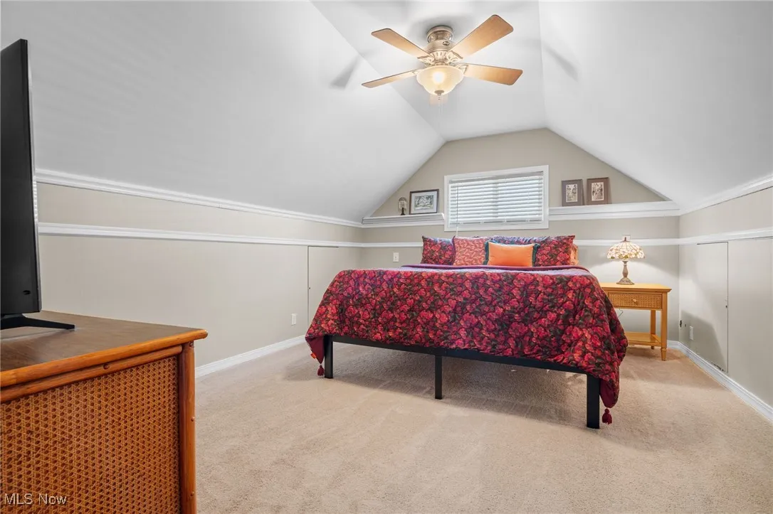 Carpeted bedroom with vaulted ceiling and a ceiling fan