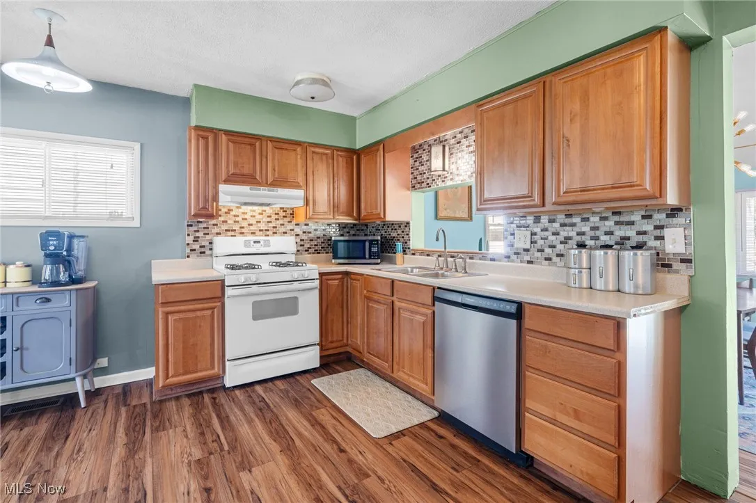 Kitchen with appliances with stainless steel finishes, tasteful backsplash, light countertops, and a textured ceiling