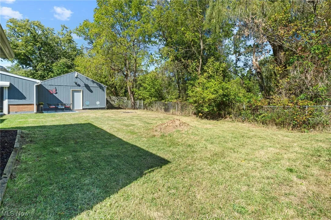 Fenced backyard with view of wooded area