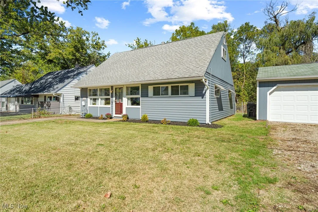 View of front of property with a shingled roof and an outbuilding