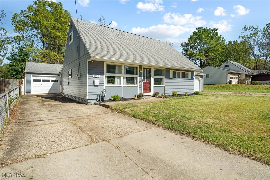 View of front of house featuring a shingled roof, an outbuilding, driveway, and a garage