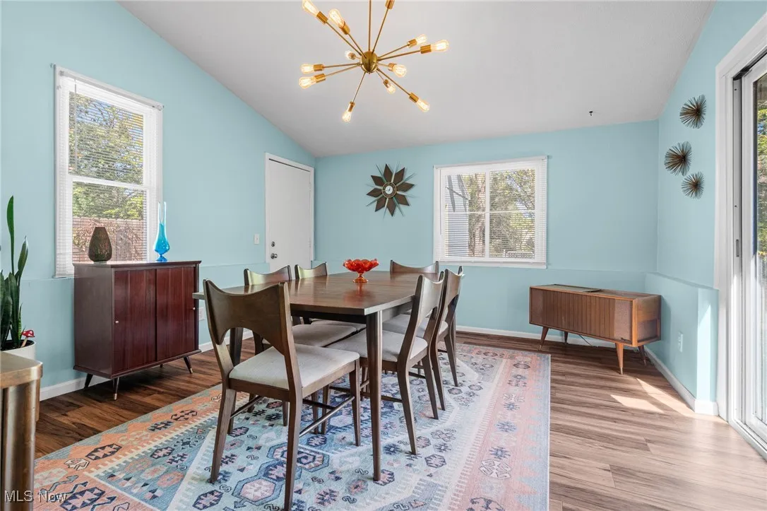 Dining area featuring vaulted ceiling, a chandelier, and wood finished floors