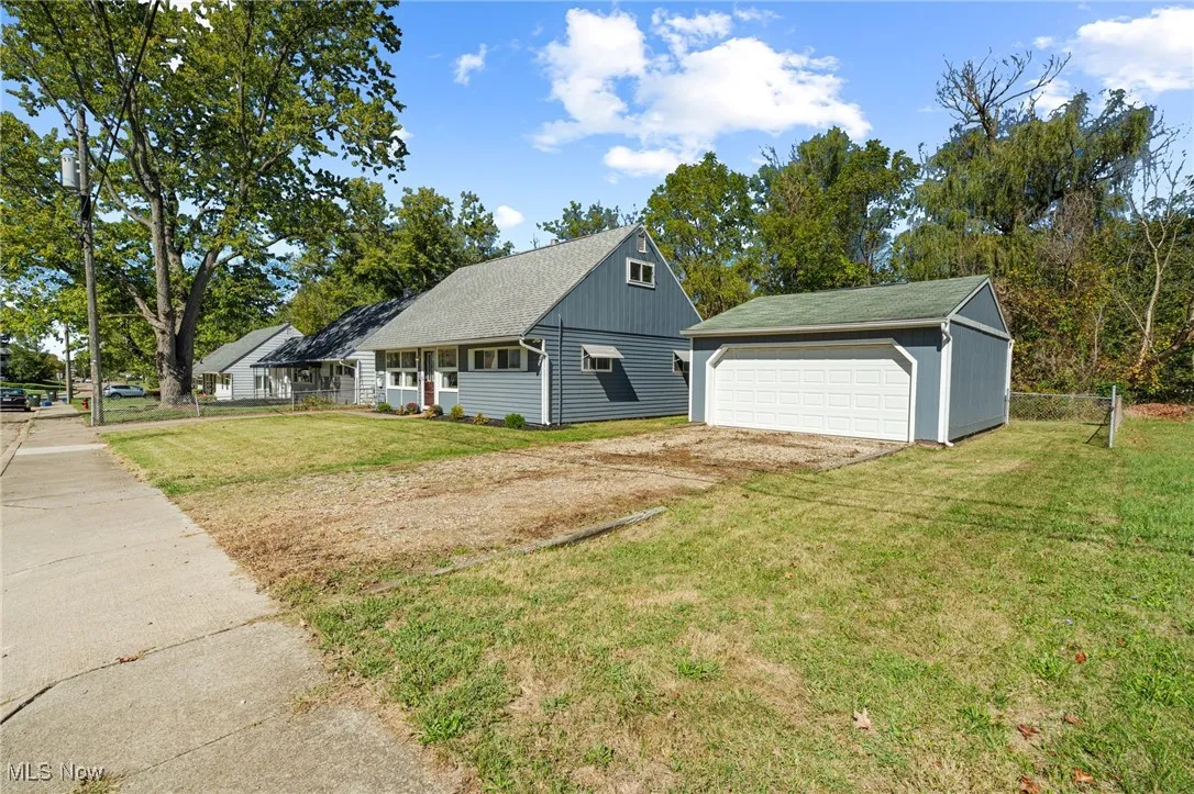 View of front of property with an outbuilding, a shingled roof, and a detached garage