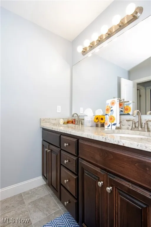 Full bath featuring double vanity and baseboards