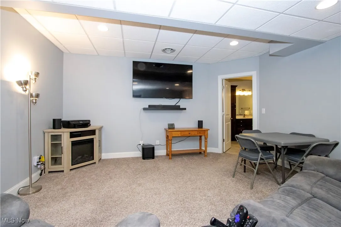 Living area featuring a drop ceiling, light carpet, and recessed lighting