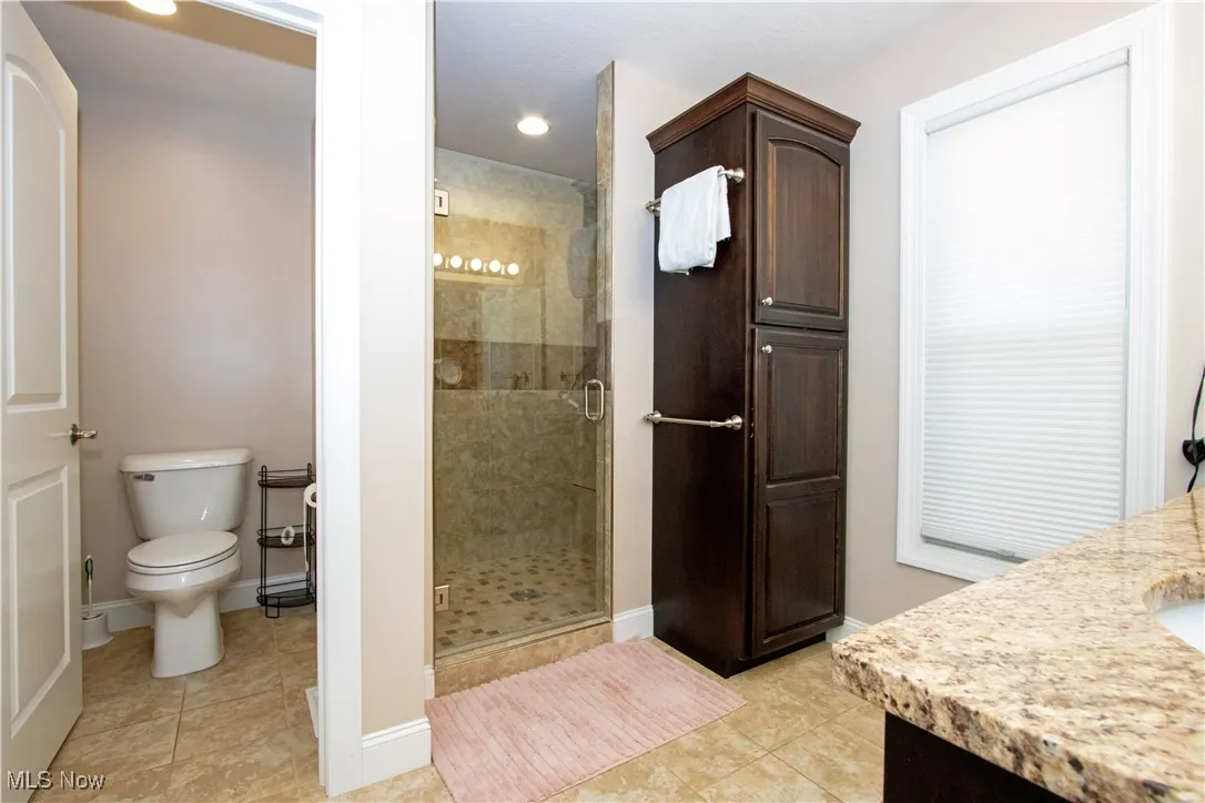 Full bath with vanity, light tile patterned flooring, a shower stall, and recessed lighting