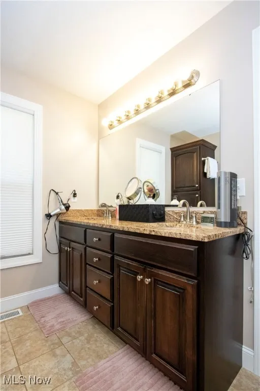 Bathroom with double vanity and light tile patterned flooring