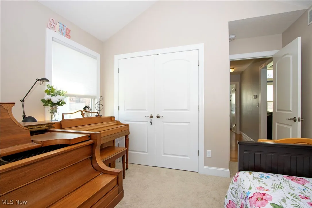 Bedroom with light carpet, a closet, and vaulted ceiling