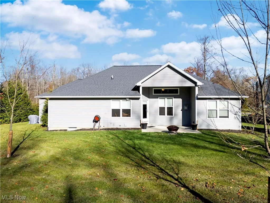 Back of property featuring a patio, roof with shingles, and a yard