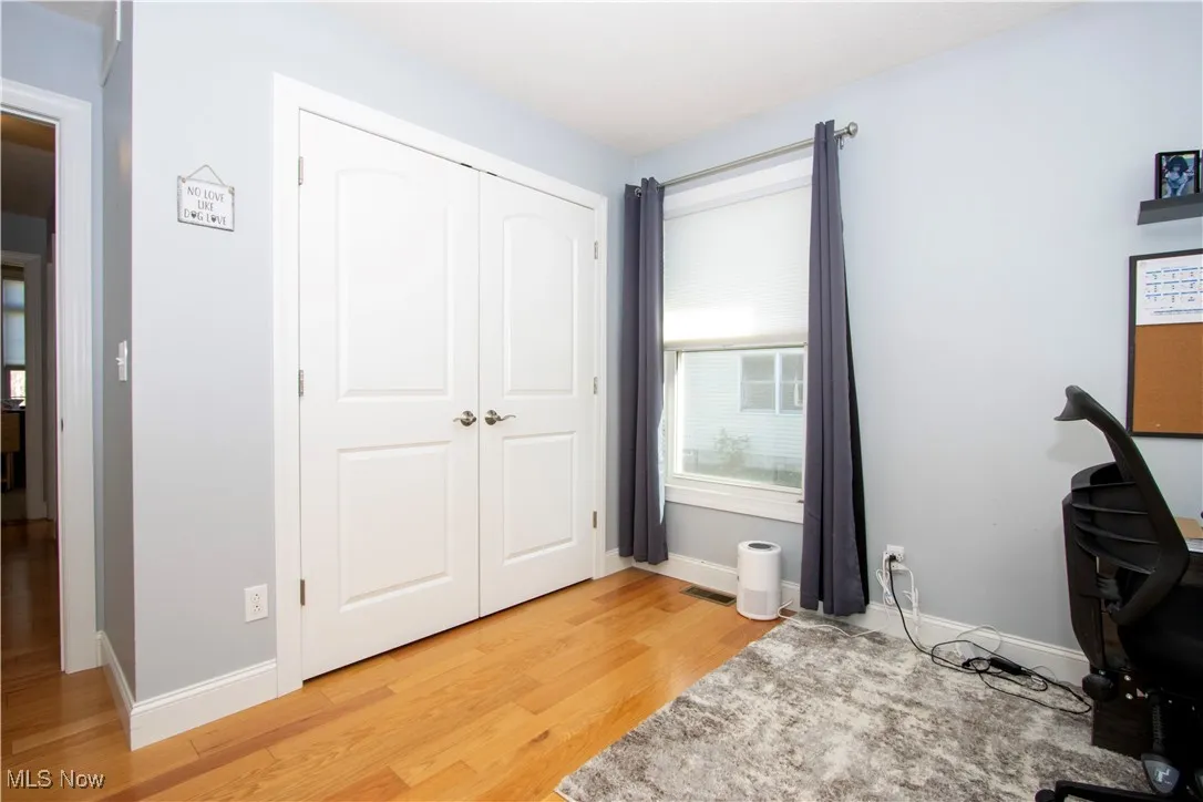 Bedroom featuring light wood-style floors, a desk, and a closet
