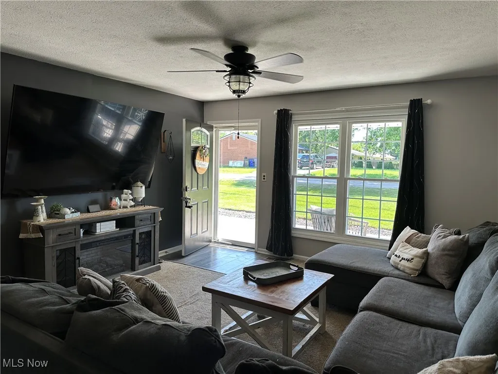 Living area featuring a textured ceiling, wood finished floors, and ceiling fan