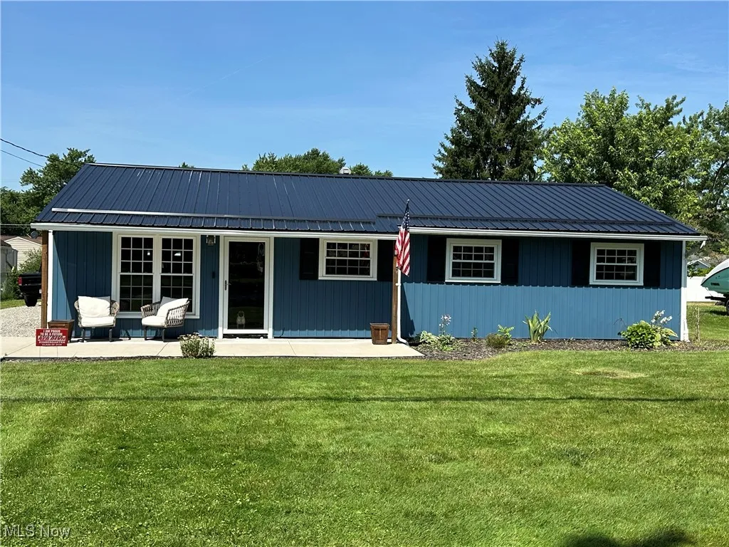 Ranch-style home with a metal roof, a front yard, and a patio area