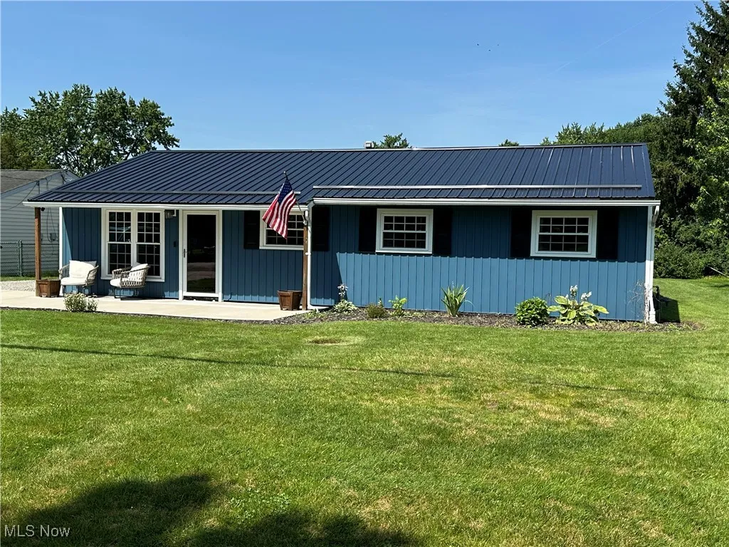 View of front of house featuring a front lawn, board and batten siding, and a metal roof