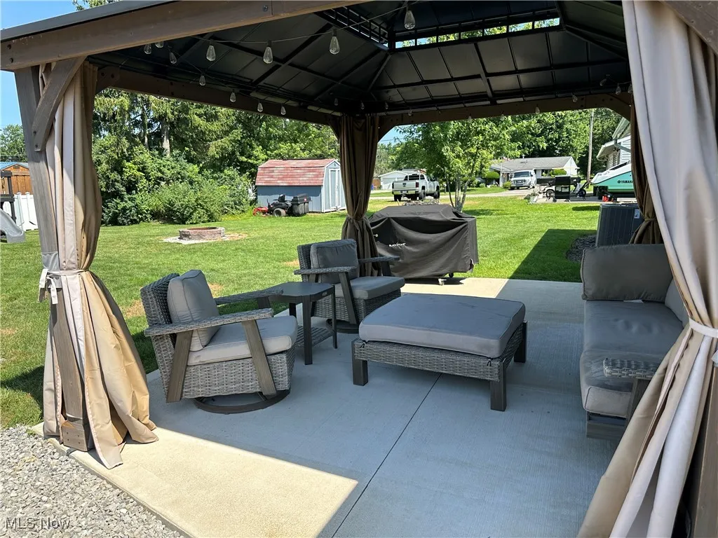 View of patio with a storage shed, an outdoor fire pit, a gazebo, and a grill