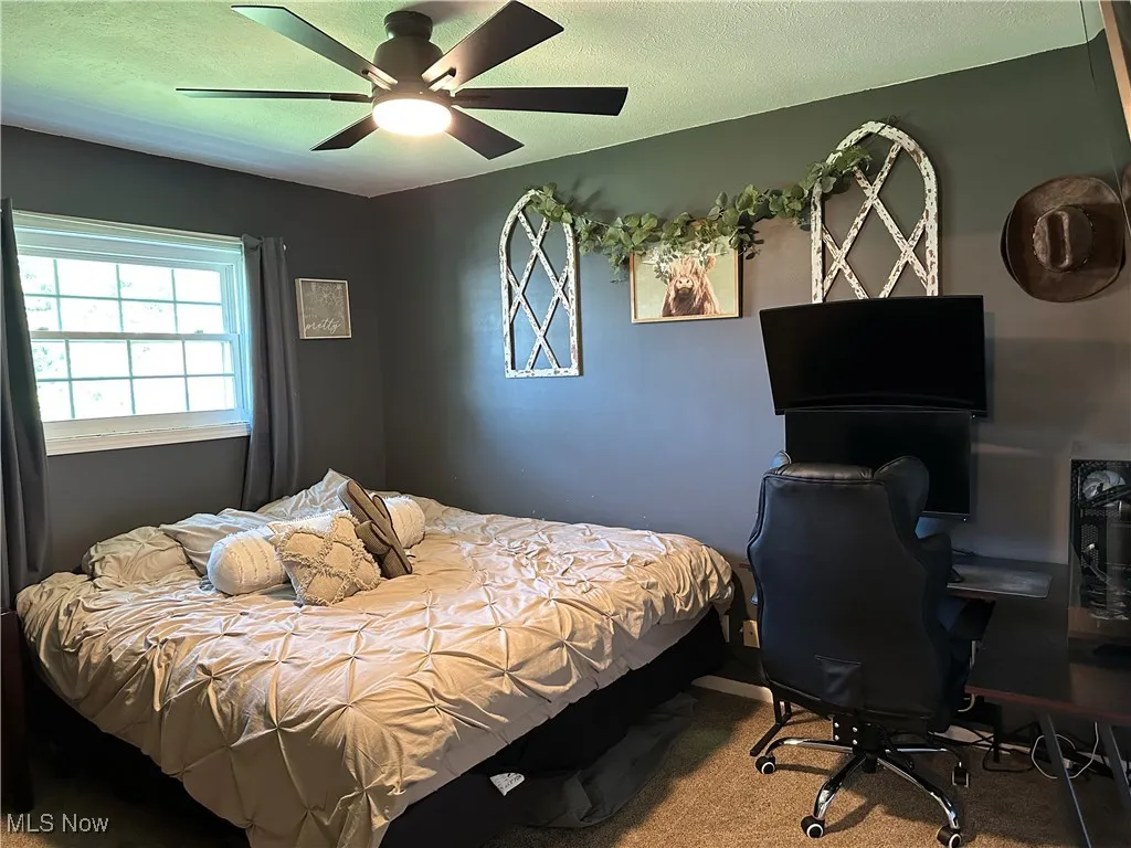 Carpeted bedroom featuring a textured ceiling and ceiling fan