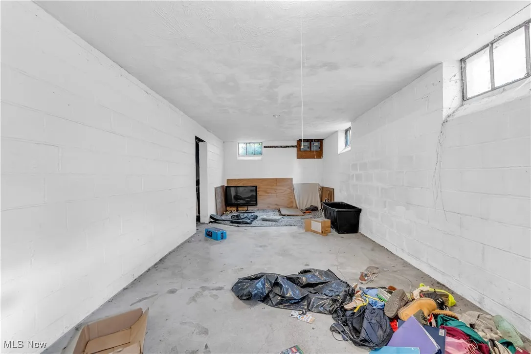 Unfurnished living room featuring concrete block wall and concrete flooring